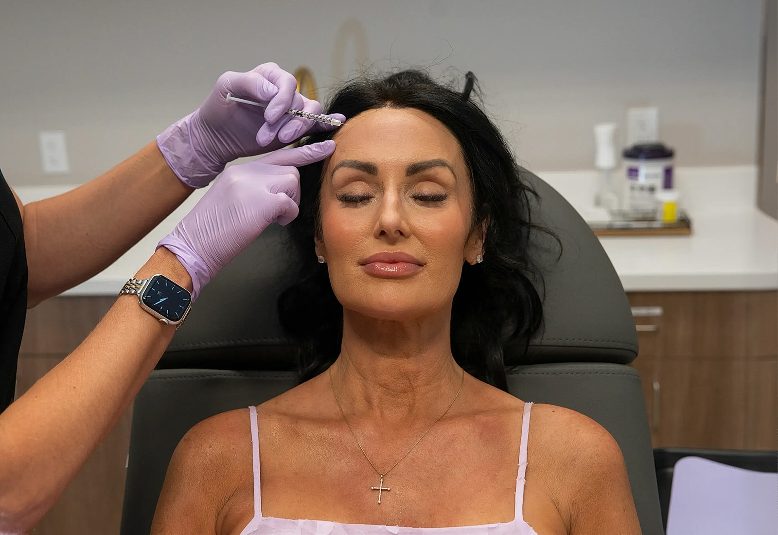 Woman receiving cosmetic procedure in clinic setting.